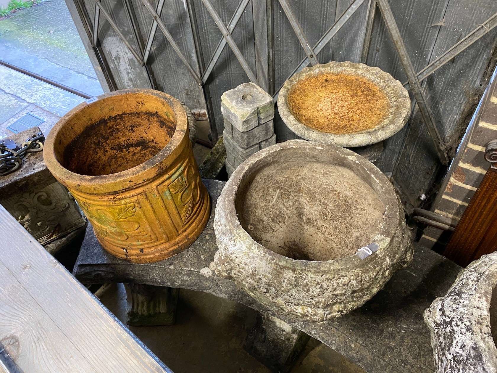Two reconstituted stone garden bird baths, a campana garden urn, circular terracotta planter and two stands, largest height 75cm